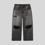 Black washed distressed jeans with large ripped knees, faded thigh detailing, and rhinestone embellishments running along both outer legs.