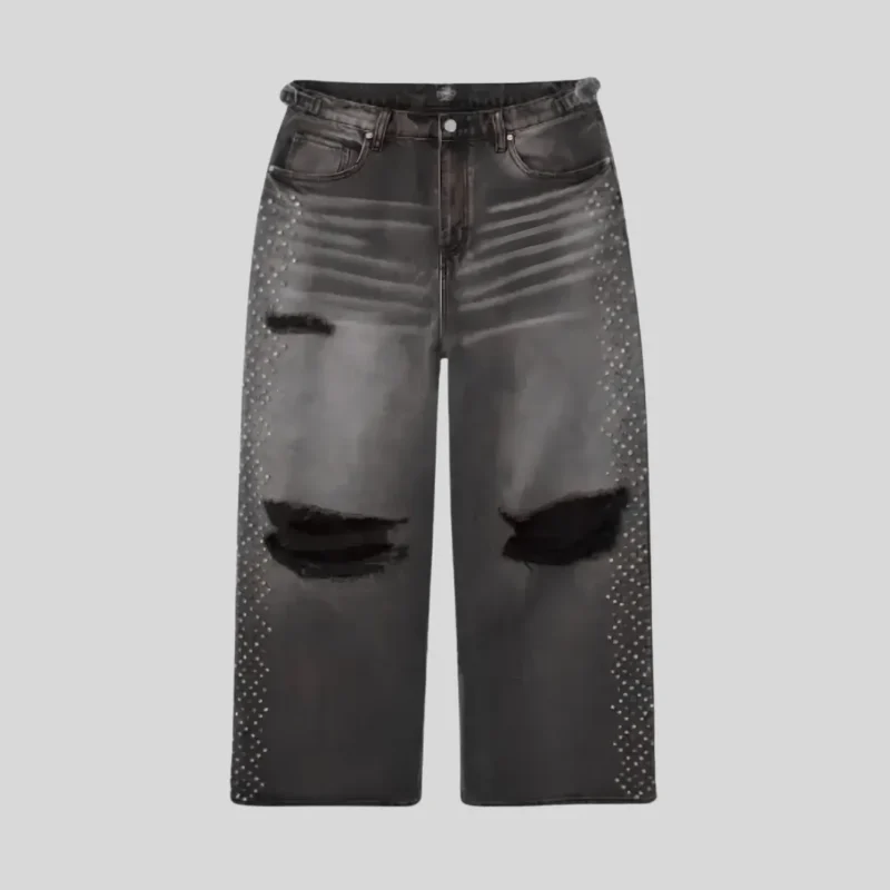 Black washed distressed jeans with large ripped knees, faded thigh detailing, and rhinestone embellishments running along both outer legs.
