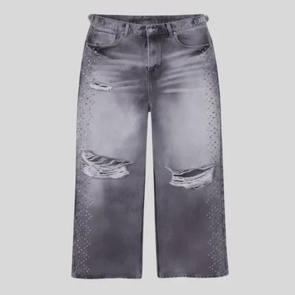 Grey washed distressed jeans with frayed ripped knees and rhinestone embellishments running along both outer legs.