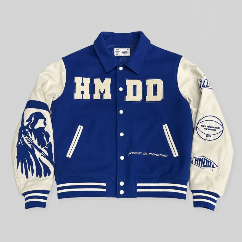 Blue and cream varsity jacket with large chenille-style chest lettering, graphic sleeve artwork, embroidered patches and striped ribbed cuffs.
